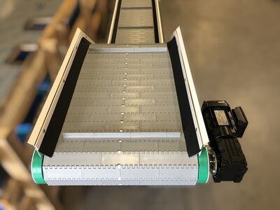 Vertikalförderer in Z-Bauform mit Stahlrahmen und Förderband im industriellen Einsatz